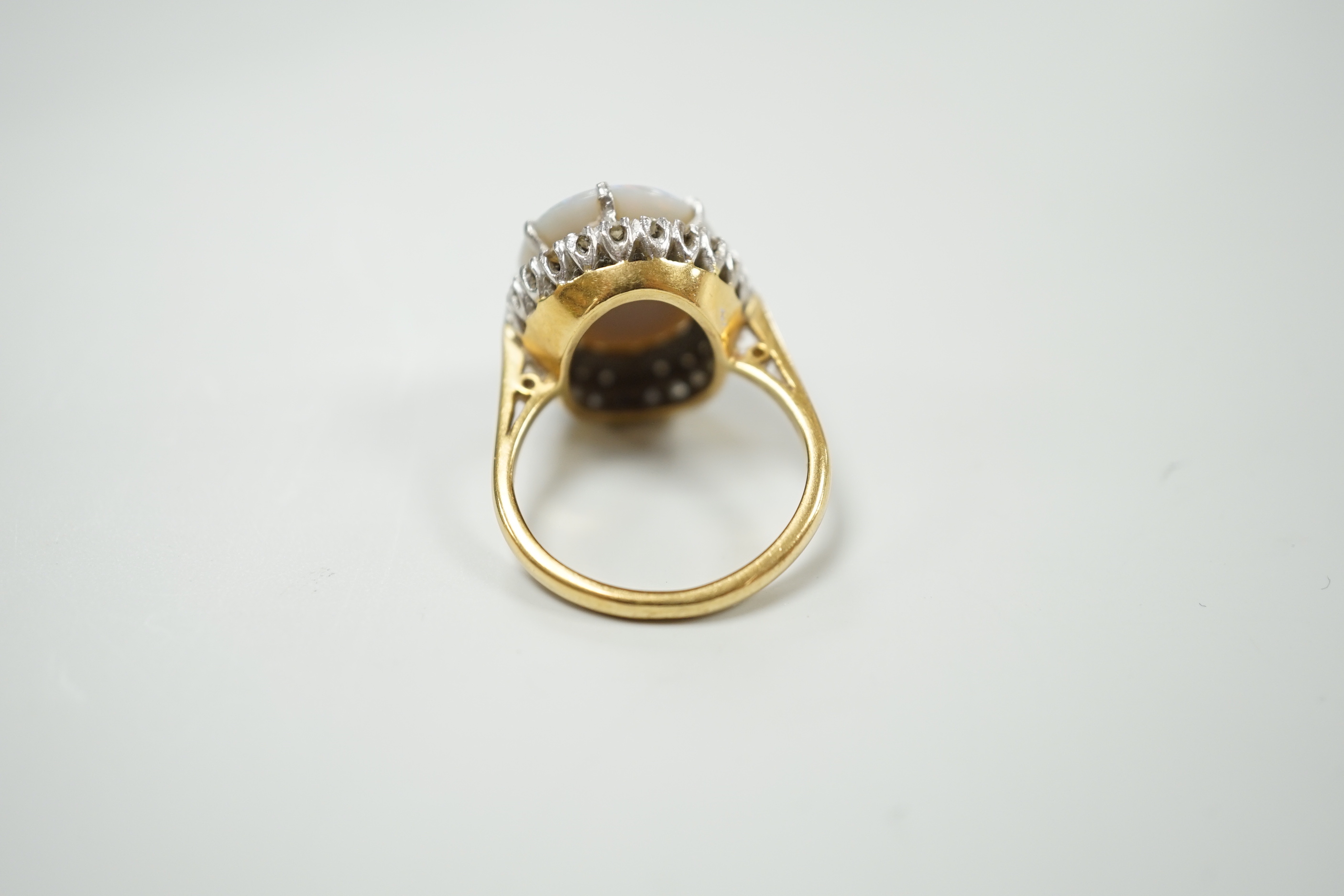 An 18ct, white opal and diamond chip set oval cluster ring, size L, gross weight 8.1 grams.